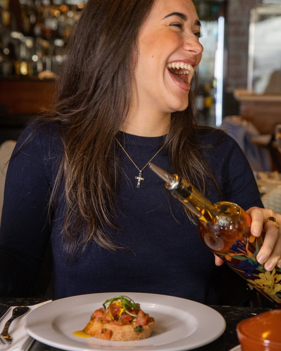 A guest laughing at the table over bruschetta and olive oil
