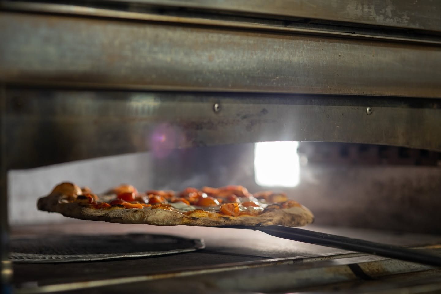 A pizza sliding into the oven