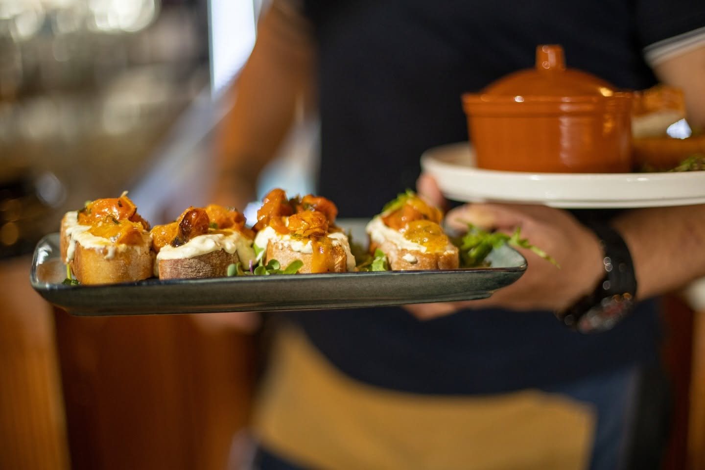 A waiter carrying a tray of bruschetta through the room
