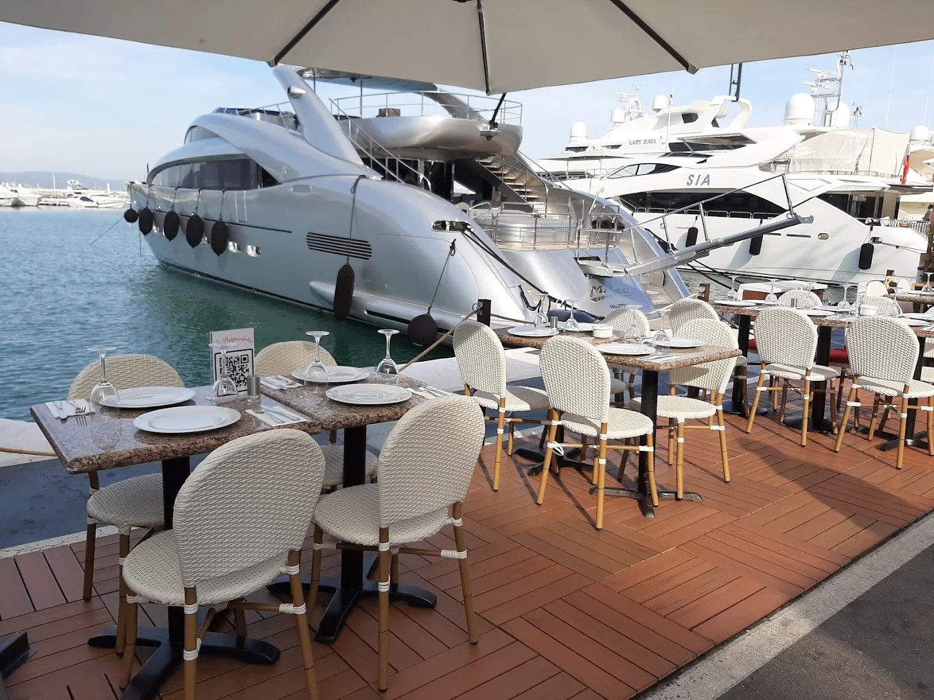 Tables laid on the deck at La Pappardella with superyachts moored a few metres away