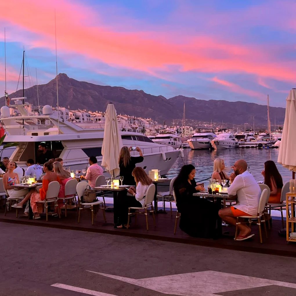 The terrace at La Pappardella at sunset, tables full, yachts and La Concha mountain behind